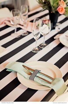 the table is set with black and white striped napkins, silverware, and wine glasses