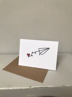 a card with a paper airplane and heart on the side, sitting on top of a table