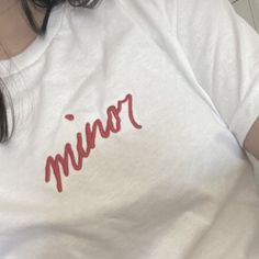 a woman wearing a white shirt with red writing on it