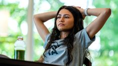 a woman sitting at a table with her hands on her head and looking off to the side