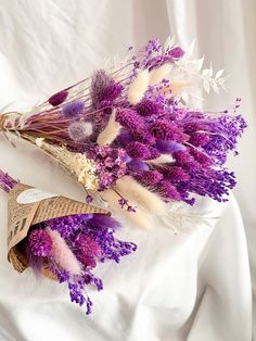 purple flowers and feathers are on a white cloth