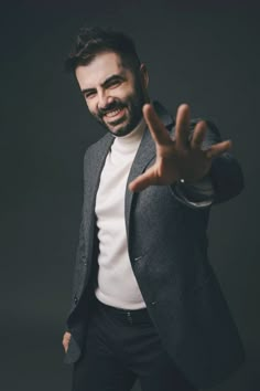 a man in a suit making the vulcan sign with his hand while wearing a white shirt and black pants