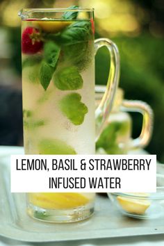 lemon basil and strawberry infused water in a glass pitcher with strawberries on the rim