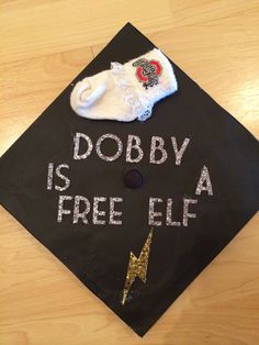 a black graduation cap with the words dobby is free elf written on it and a pair of white socks