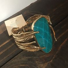 This Cuff Bracelet Has A Beautiful Large Blueish Green Glittering Stone On The Center Of It With Gold Toned Metal Leaf Details Wrapping Around. It Has A Middle Hinge That Opens The Bracelet. Although It Looks Heavy The Bracelet Is Light Weight. Blueish Green, Gold Cuff Bracelet, Gold Bracelet Cuff, Metal Leaves, Gold Cuffs, Teal And Gold, Gold Tone Metal, Womens Jewelry Bracelets, Blue Gold