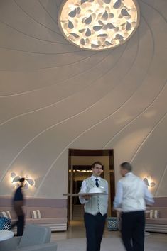 two men in suits are walking through the lobby