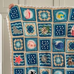 a person holding up a crocheted blanket with sea animals on it