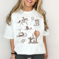 Step into the wild, wild west with our Western Cowgirl Graphic Tee! The vintage style on this Comfort Colors t-shirt is a must-have for any cowgirl at heart. This tee is perfect for adding a touch of western aesthetic to your wardrobe. Whether you're looking for a fun graphic tee for yourself or to gift to a best friend our Cowgirl Tee is the perfect choice! Make sure to size up for that trendy oversized look! Features: 100% ring spun cotton, 30 singles Garment dyed for that lived in feel and al Trendy Crew Neck T-shirt For Ranch, Trendy White Tops For Ranch, Retro Crew Neck Tops For Western-themed Events, Casual White T-shirt For Western-themed Events, Western-themed Graphic Print Cotton Tops, Retro Western Style Short Sleeve Top, Cotton Graphic Print Top For Western-themed Events, White Crew Neck Tops For Western-themed Events, Retro Summer Tops For Western-themed Events