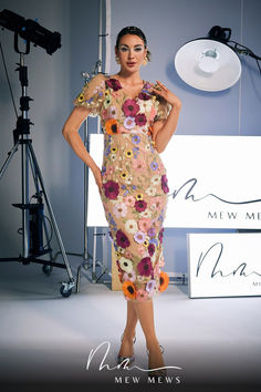 a woman standing in front of a camera wearing a dress with flowers on the side