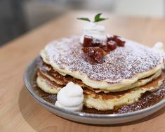 pancakes on a plate topped with butter and bacon, sitting on a wooden table top