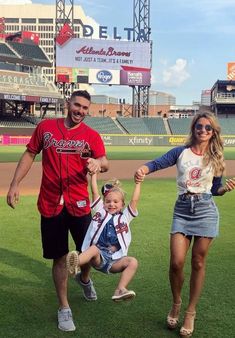 a man, woman and child walking across a baseball field