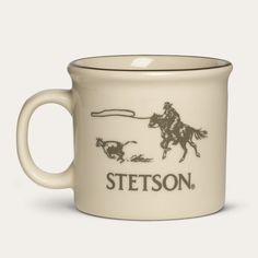 a white mug with a horse and rider on it that says stetson in brown lettering