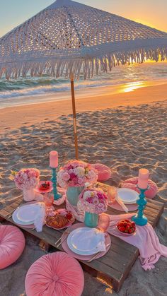 a table set up on the beach at sunset