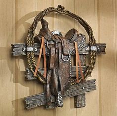 a wooden wall hanging with a cowgirl's saddle on it and rope around the neck