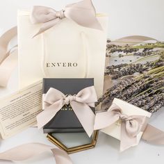 an open gift bag sitting on top of a table next to lavenders and ribbons