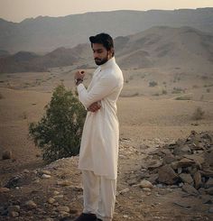 a man standing in the desert with his hands on his hips and looking at something