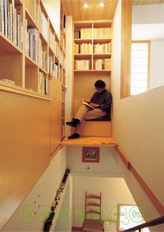 a man sitting on top of a bookshelf in a room filled with books