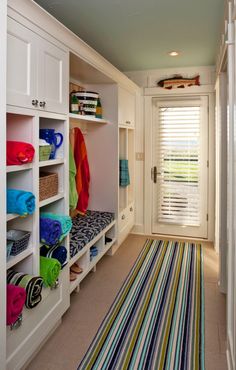 a white closet filled with lots of towels and other items next to a window covered in shutters