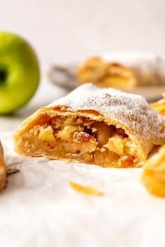 an apple pie is cut in half and sitting next to some other fruit on the table