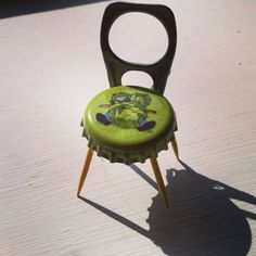 there is a small green chair with a frog on it's back and legs