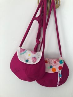 two purses hanging from hooks on a wall