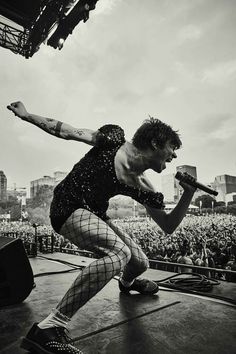 a man in fishnet tights is on stage with his arms stretched out as he holds a microphone