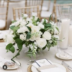 a bouquet of white flowers sitting on top of a table next to plates and napkins