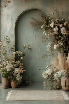 three vases filled with flowers on top of a white table cloth next to an arch