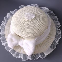 This elegant straw hat features a plush bow embellishment, intricately adorned with delicate lace trimmings. The hat's crown is further enhanced with a heart-shaped lace applique, adding a touch of charm and sophistication.  Please note: The price includes one hat only. Cute Adjustable Hat With Bow, White Beach Hat With Bow, White Hat With Ribbon And Short Brim, White Short Brim Hat With Ribbon, Straw Hats With Bow And Short Brim, Spring Brimmed Hat With Ruffles, Spring Hat With Ruffles And Curved Brim, Spring Hats With Ruffles, Spring Hats With Ruffles And Curved Brim