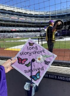 a purple and white sign with words on it in front of a baseball diamond at a stadium