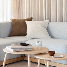 two coffee tables sitting next to each other on top of a wooden table in front of a couch