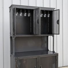 a metal cabinet with three wine glasses on it's top and two doors open