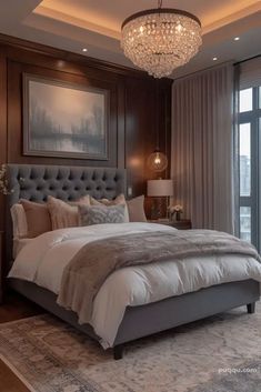 a bedroom with a large bed, chandelier and window overlooking the cityscape