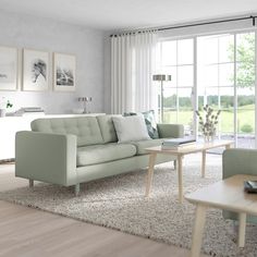 a living room filled with furniture next to a large glass wall window covered in white curtains