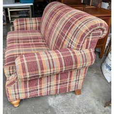 a plaid couch sitting on top of a floor next to a wooden table and chair