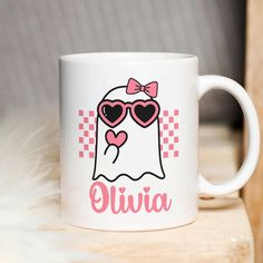 a white coffee mug with a pink bow and heart shaped sunglasses on it's face