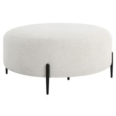 a white ottoman sitting on top of a black metal frame base with legs in front of it