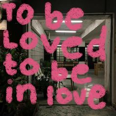 the words to be loved by someone in love are painted on a glass door with pink paint