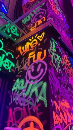 colorful neon lights and graffiti on the side of a building