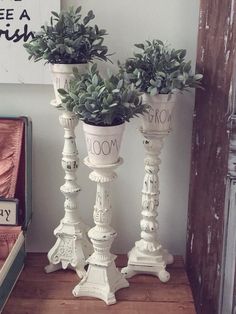 two white vases with plants on them sitting on a wooden table next to a book