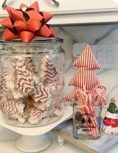 a glass jar filled with candy canes on top of a counter next to other christmas decorations