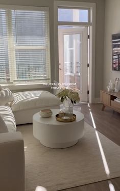 a living room with white furniture and large windows