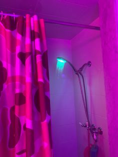 a shower with pink and purple lights in the shower stall next to a red curtain