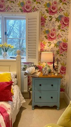 a bedroom with flowers on the wall and a blue dresser in front of a window