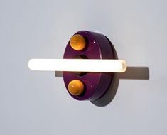 a purple wall light with two orange lights on it's side and one yellow light at the end