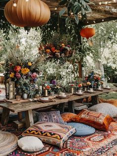 a wooden table topped with lots of pillows and vases filled with flowers on top of it