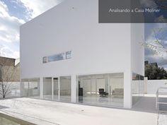 a large white building with glass doors and windows on the outside, in front of some trees