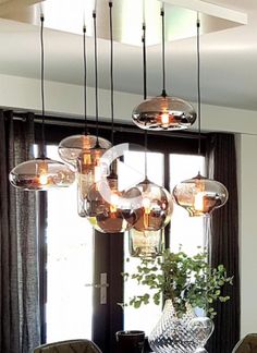 a dining room table with chairs and lights hanging from it's centerpieces