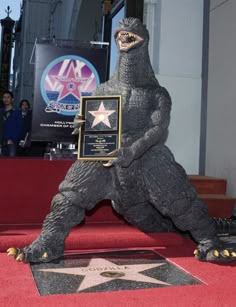 godzilla statue on hollywood walk of fame with plaque in hand and star on the ground