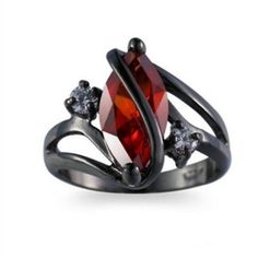 a silver ring with an orange stone and two white diamonds on the side, set in black gold